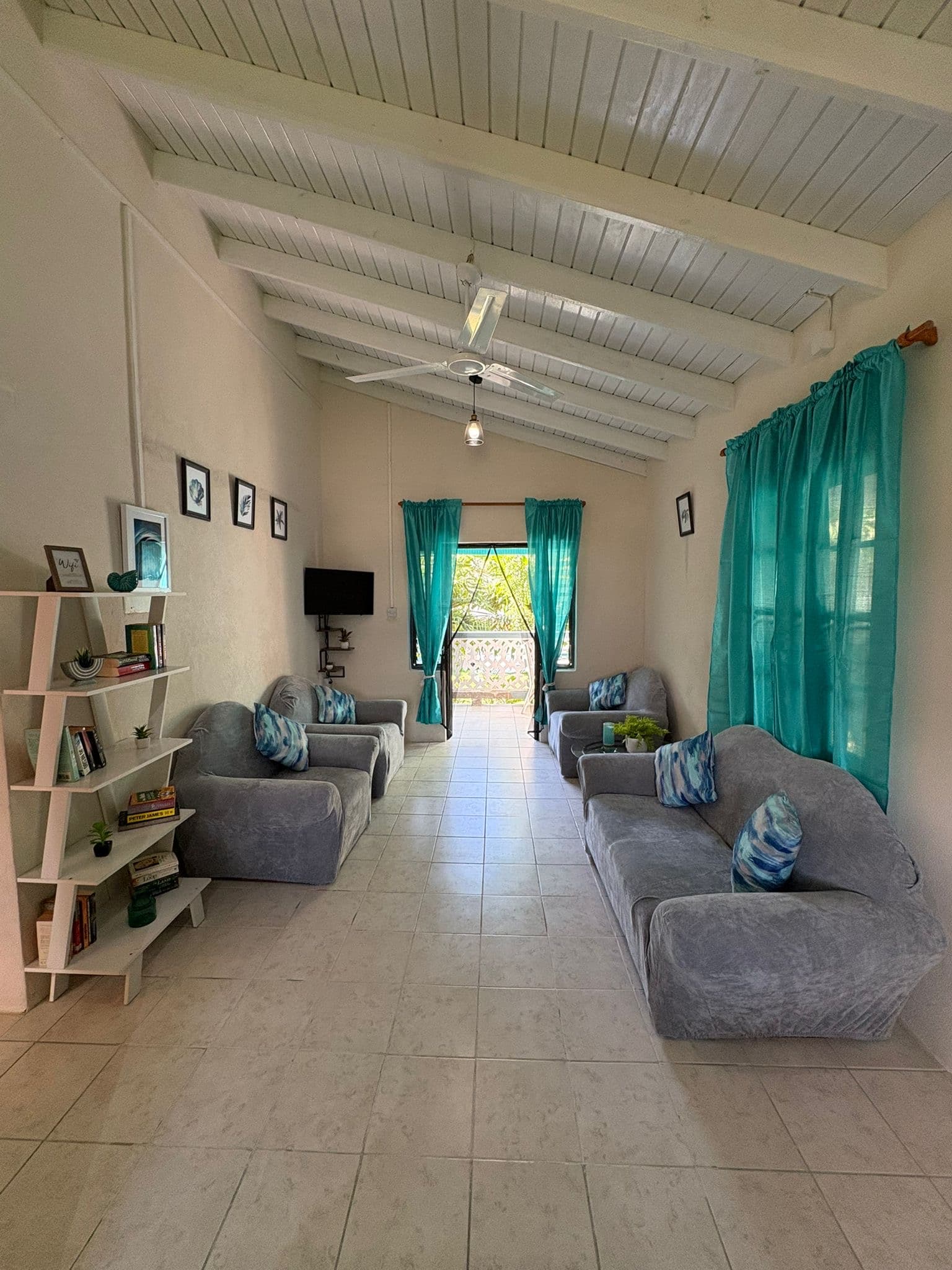 Living room inside the Balcony Suite with high ceilings and teal curtains.