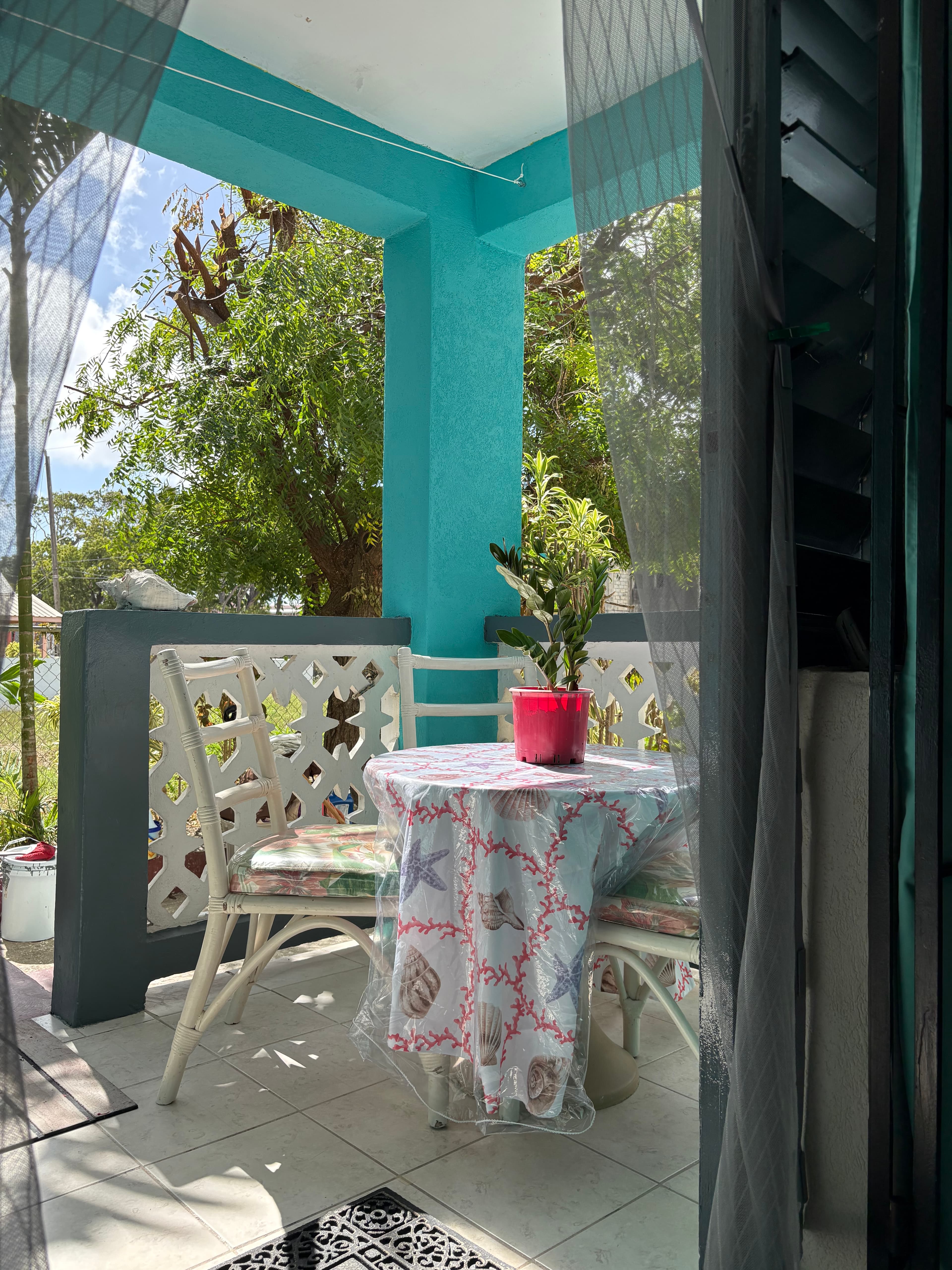 Private covered patio at the Garden Suite with leafy greenery and tropical blue walls.