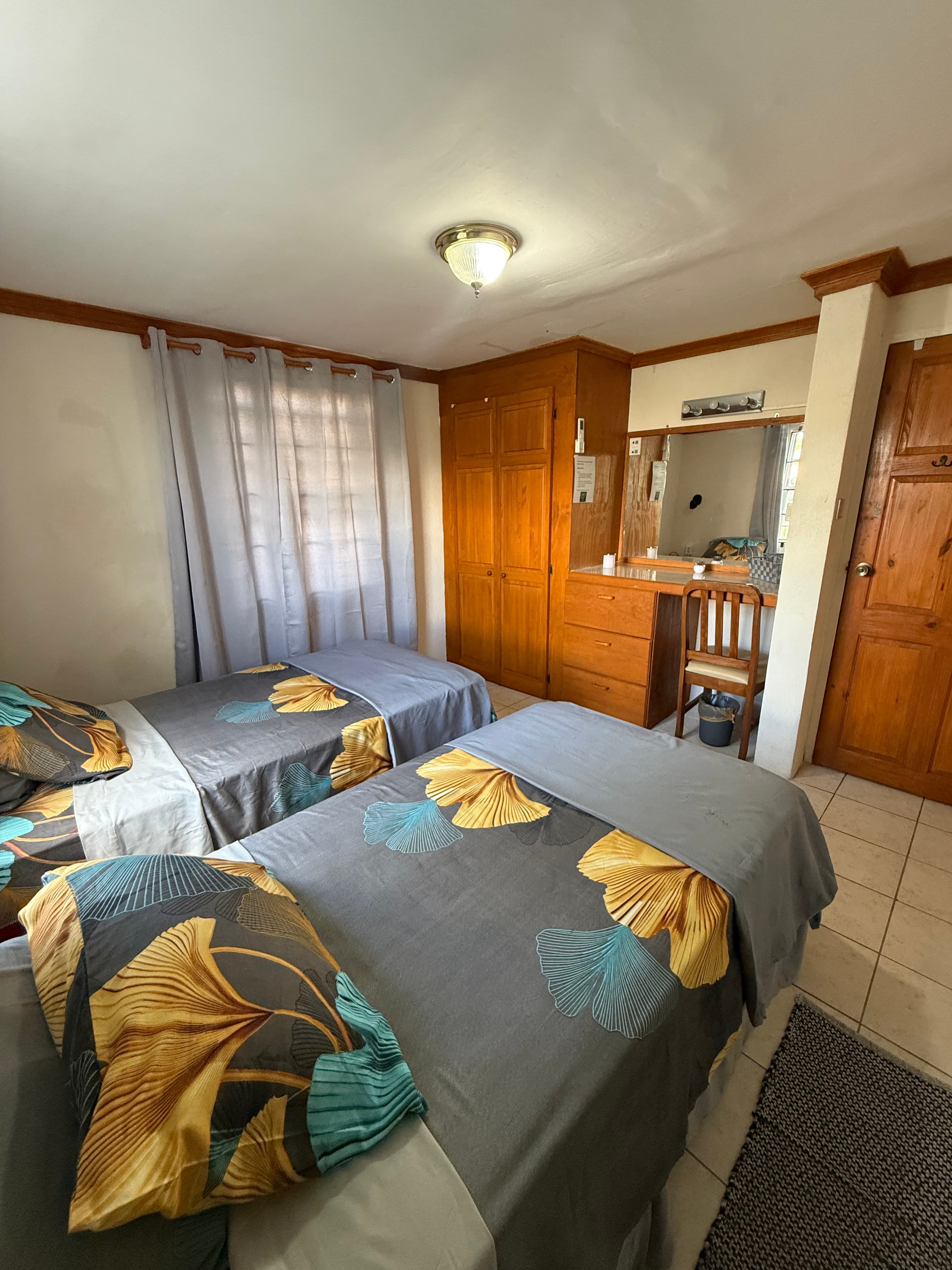 Bedroom inside the Garden Suite with wood wardrobes and patterned bedding.