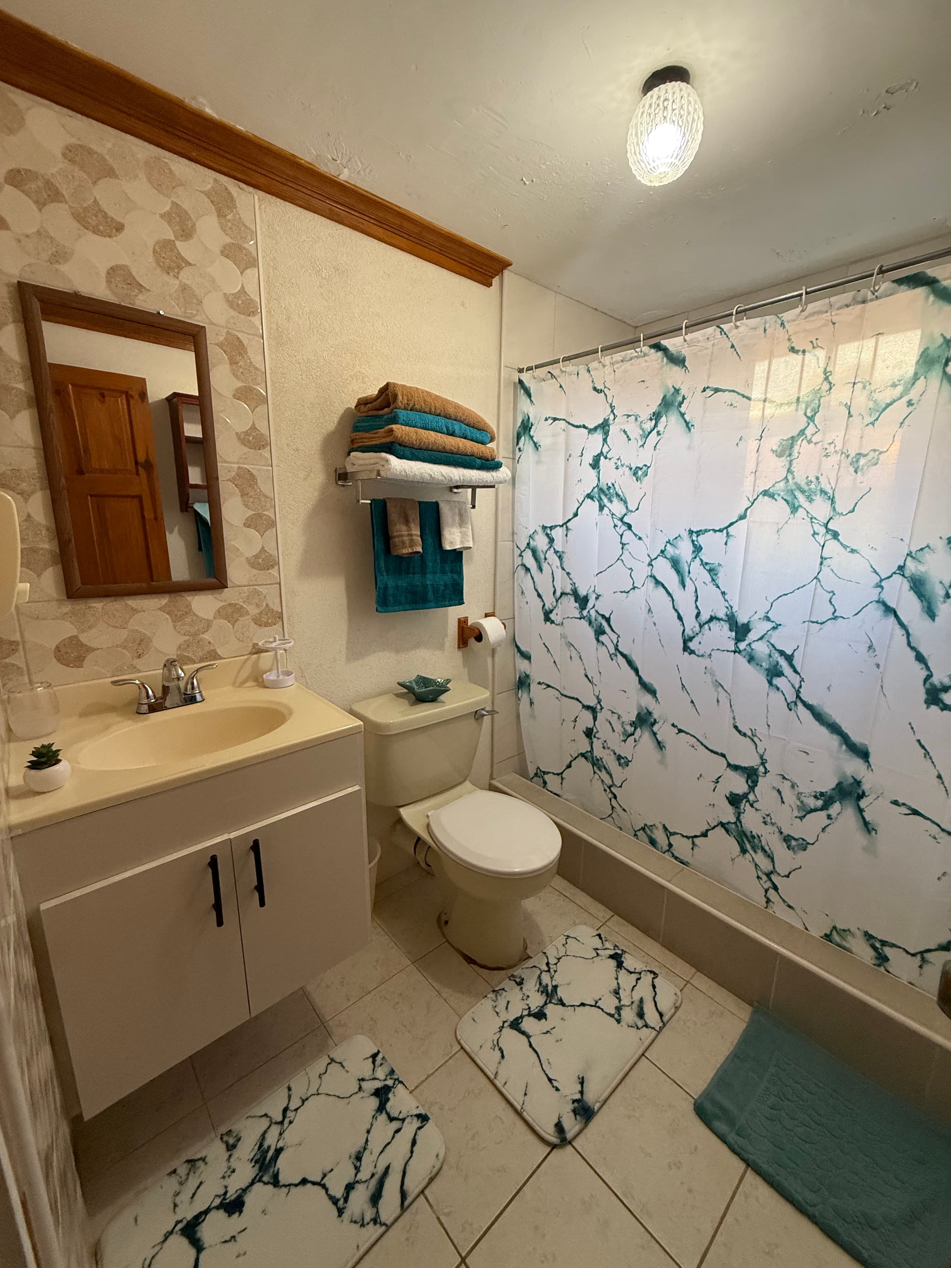 Bathroom at the Garden Suite with marble-pattern shower curtain and bright vanity.