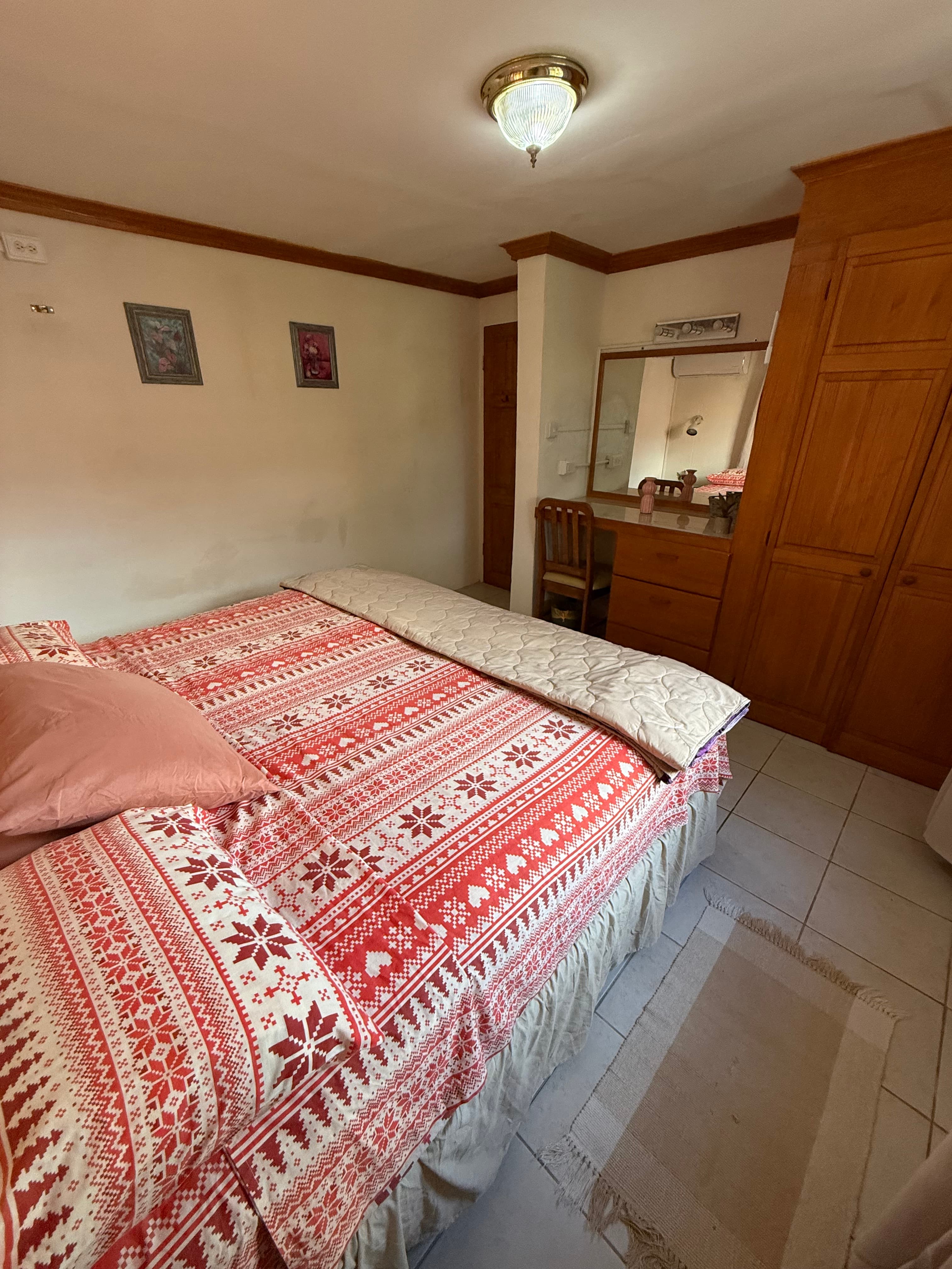 Second bedroom inside the Garden Suite with warm wood storage and coral patterned bedding.